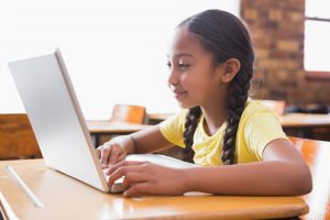 Girl in yellow shirt on computer. Coding classes for kids